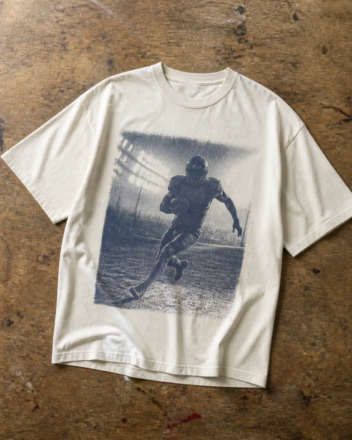 Washed cream football-inspired graphic T-shirt on a print-shop table