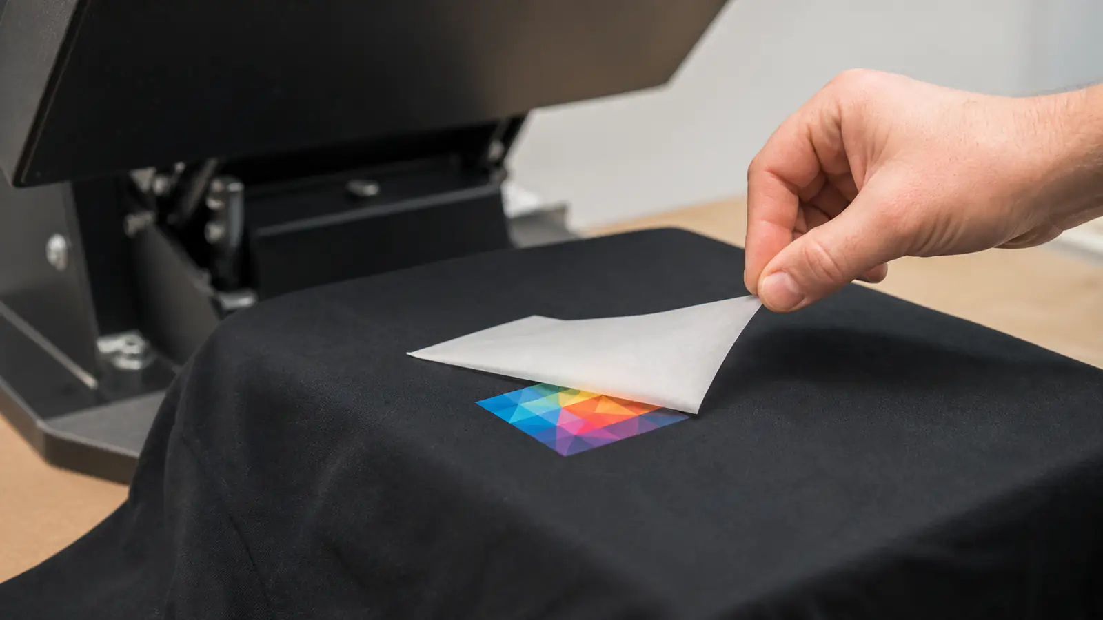 Print operator peeling an opaque DTF carrier from a geometric print sample