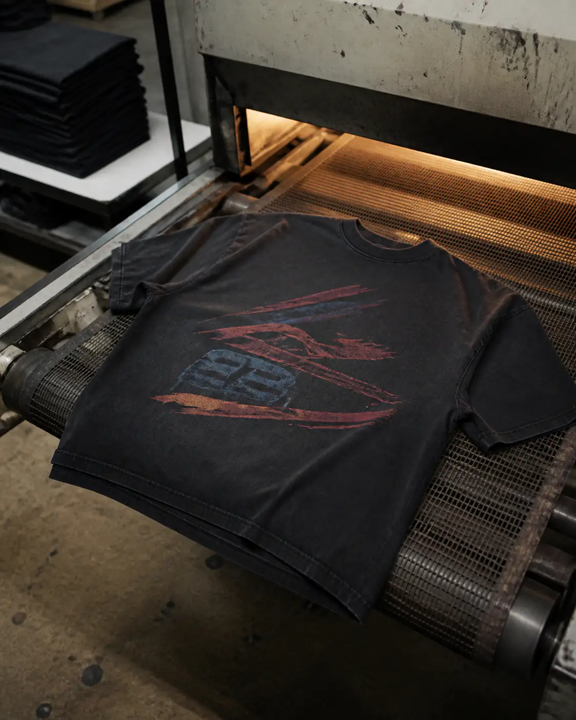 Washed black T-shirt with a distressed two-color print exiting a conveyor dryer